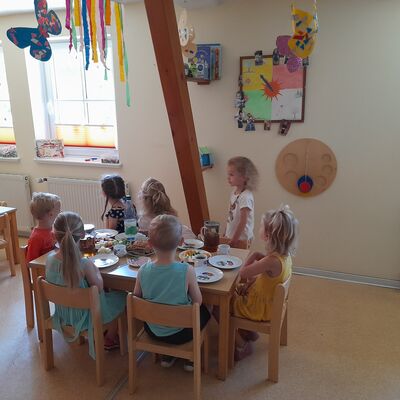 Bild vergrößern: Kinder der Kindertagesstätte sitzen im Gruppenraum an einem Tisch und essen.